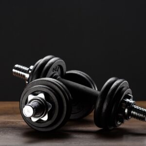 Closeup shot of two dumbells placed on dark wooden surface